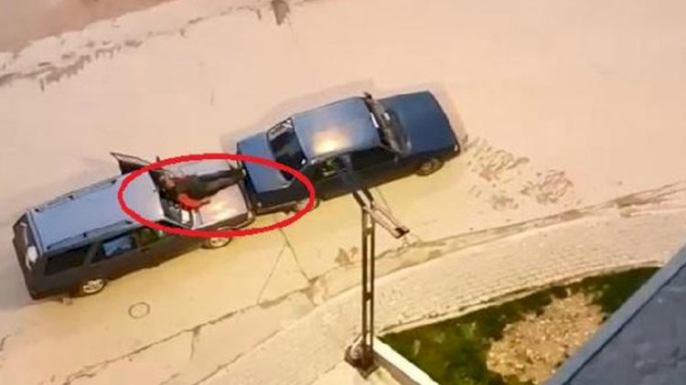 Otomobilin kaputuna oturup ayaklarıyla öndeki aracı itti
